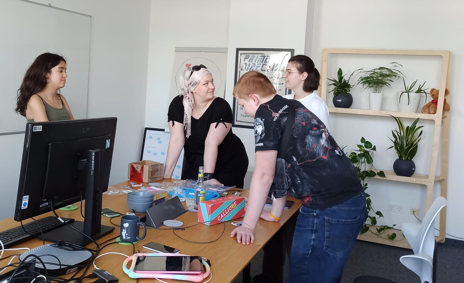 Malva, Nara, Enrico und Karo lehnen auf dem Tisch und reden