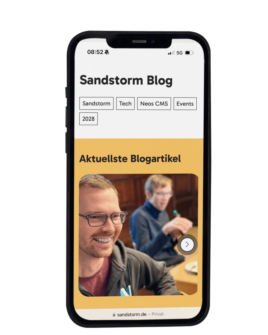 KI generiert: Das Bild zeigt einen Screenshot einer Blog-Seite namens "Sandstorm Blog" auf einem Smartphone. Der Bildschirm zeigt die Kategorien und den aktuellen Blogartikel mit einem Foto von zwei lächelnden Personen.