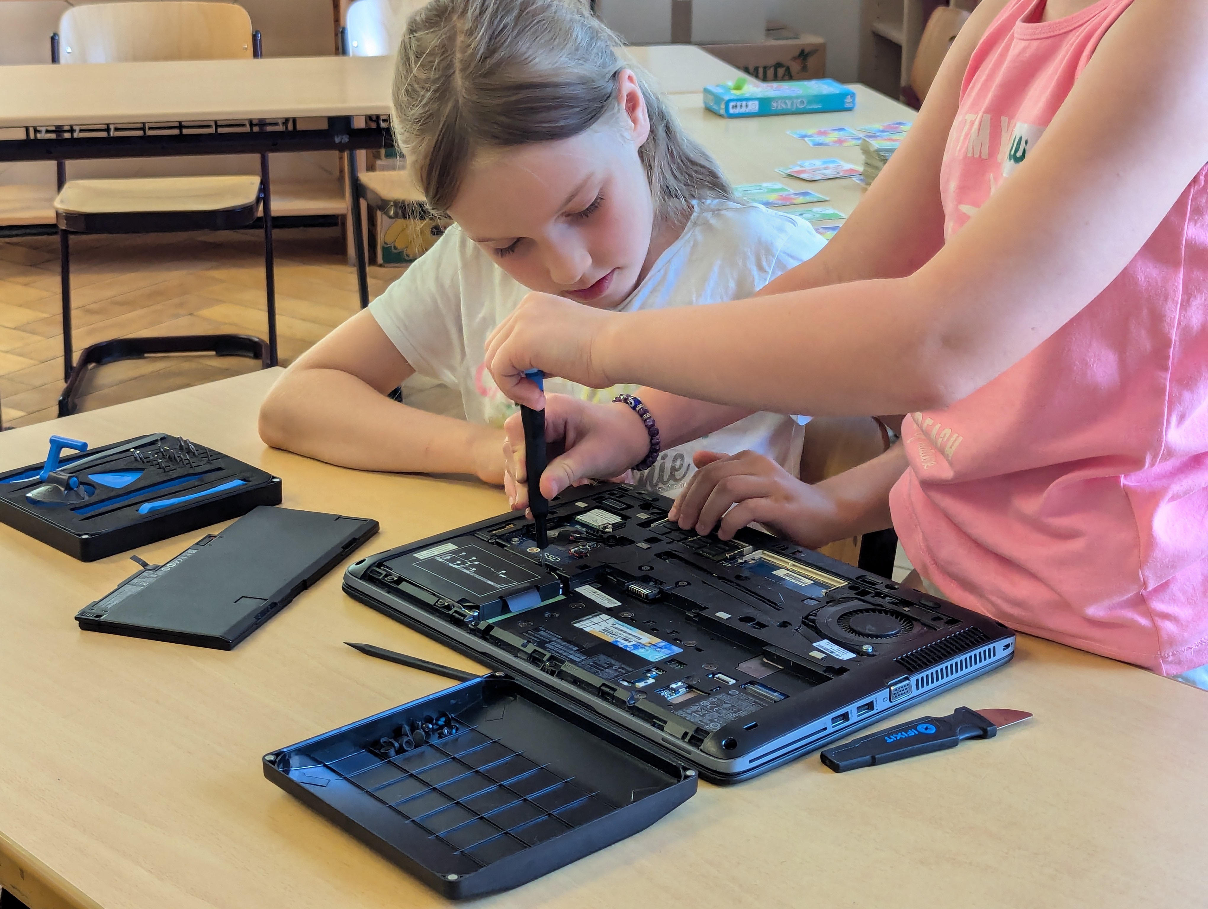 Zwei Grundschülerinnen schrauben einen Laptop auf