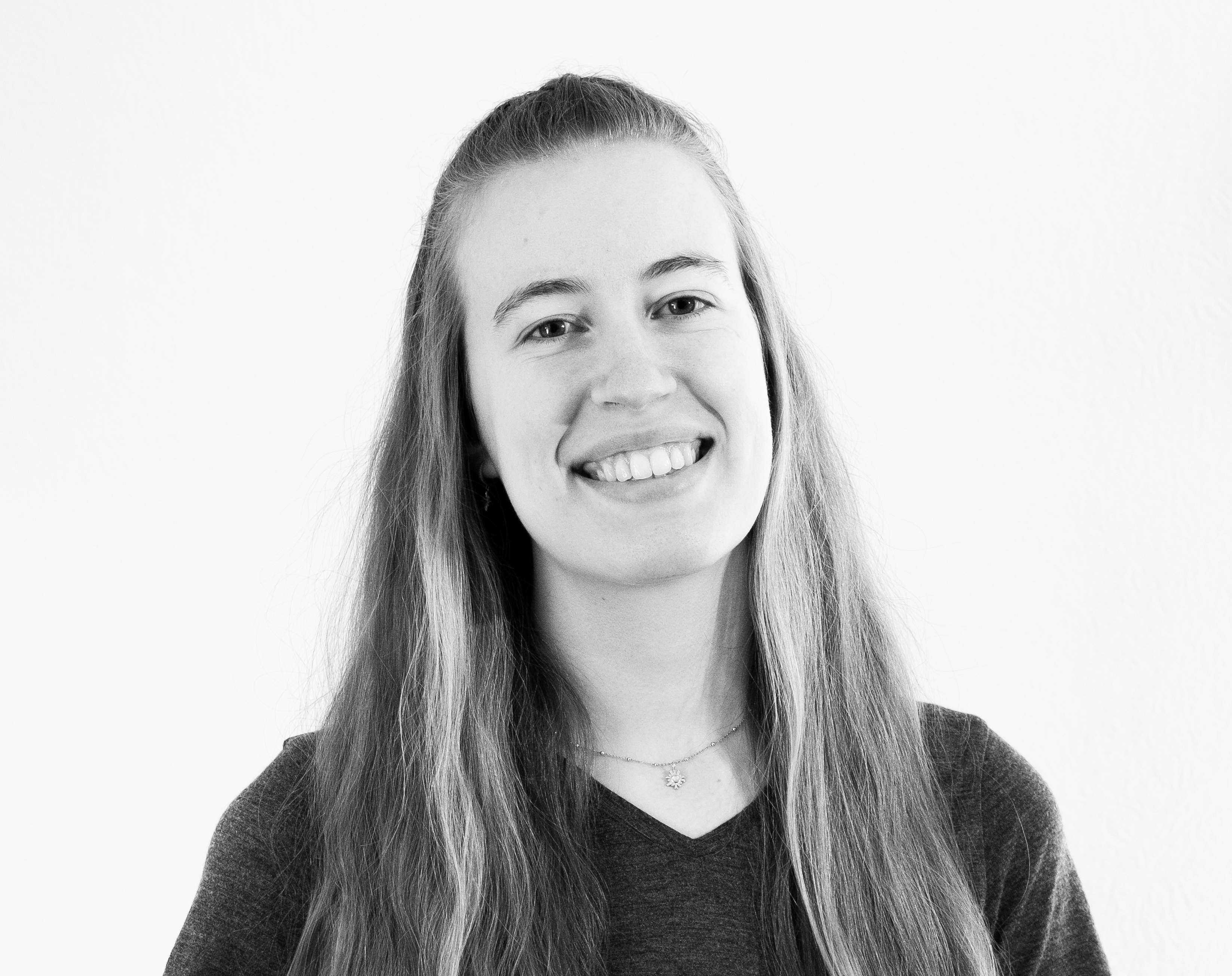 KI generiert: Das Bild zeigt eine lächelnde Frau mit langen, glatten Haaren und einem dunklen Pullover vor einem neutralen Hintergrund.