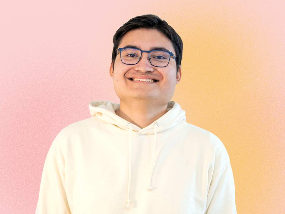 KI generiert: Das Bild zeigt einen lächelnden Mann mit Brille, der einen weißen Hoodie trägt, vor einem pastellfarbenen Hintergrund.