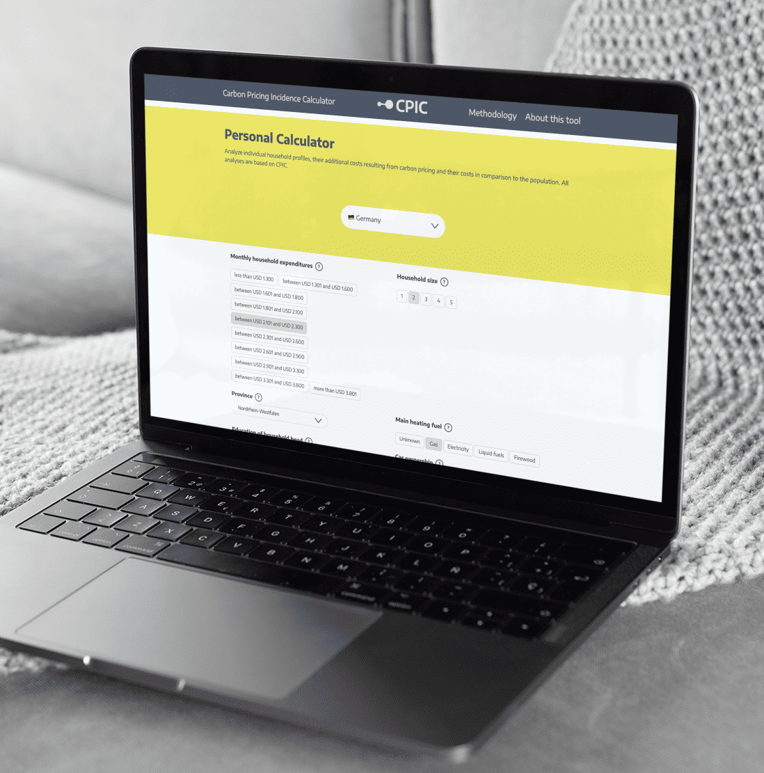 KI generiert: Das Bild zeigt einen Laptop mit einem geöffneten Browserfenster, das eine Webseite mit dem Titel "Carbon Pricing Incidence Calculator" anzeigt, auf der ein persönlicher Rechner für Haushaltsausgaben und Heizkosten in Deutschland zu sehen ist.
