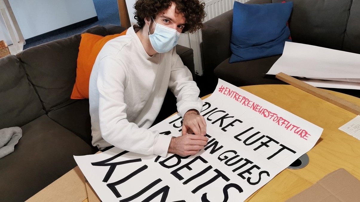 Person bastelt Klimastreik-Schild mit Text: Dicke Luft ist kein gutes Arbeitsklima