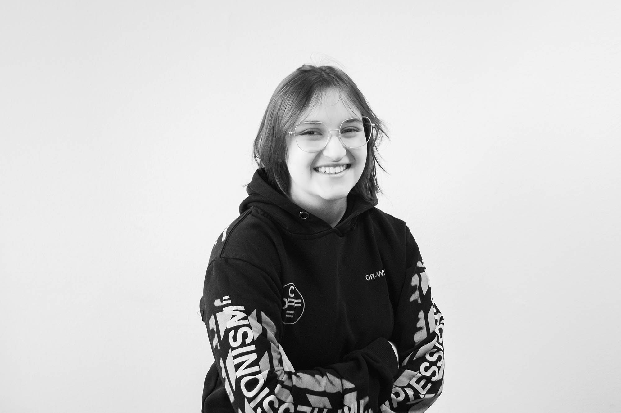 KI generiert: Das Bild zeigt eine lächelnde Frau in einem schwarzen Pullover mit einem auffälligen, weißen, grafischen Muster, das sich über den gesamten Pullover erstreckt.