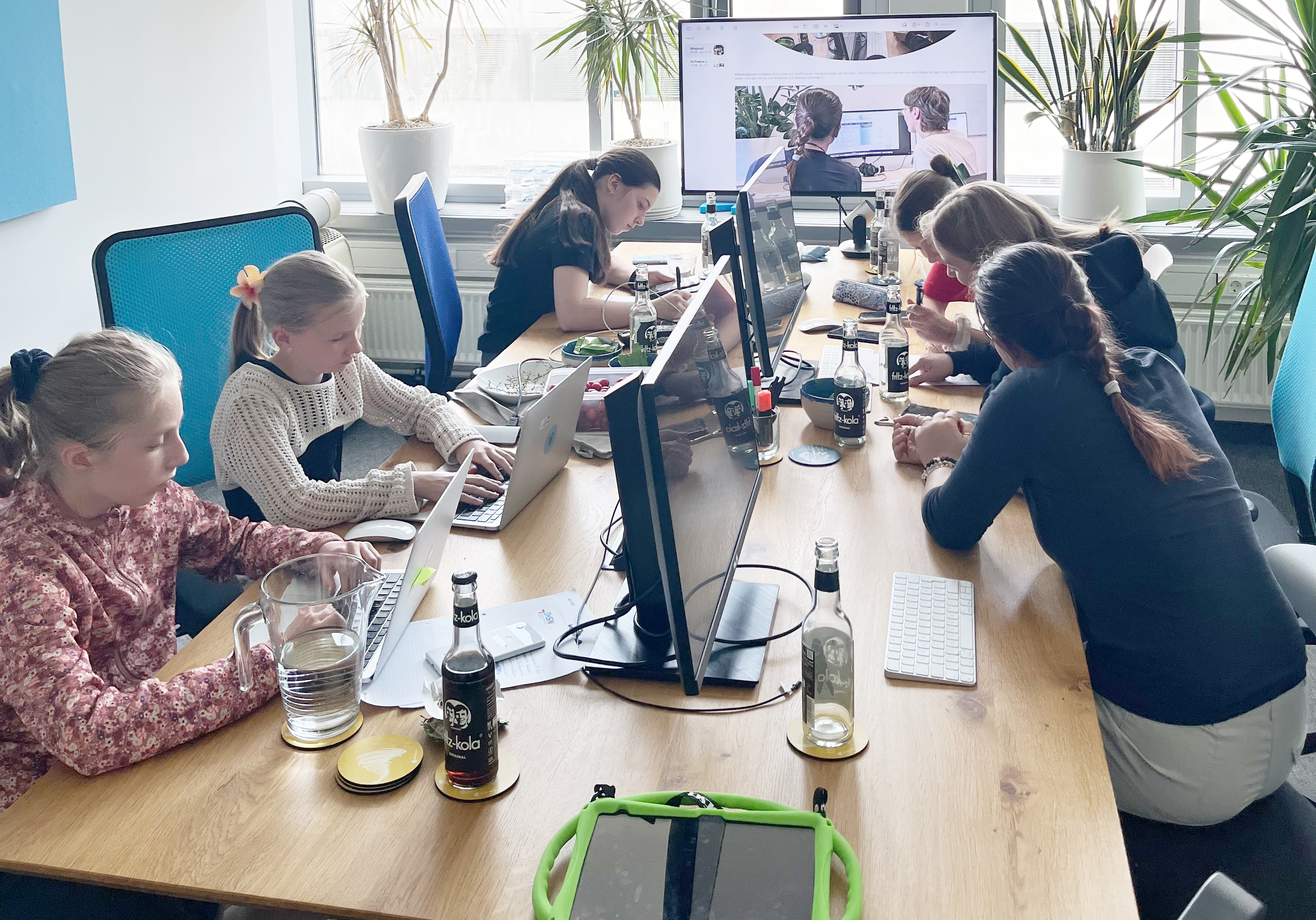 KI generiert: Mehrere Mädchen sind an Computern in einem Büro versammelt, um an einem Projekt zu arbeiten oder zu lernen.