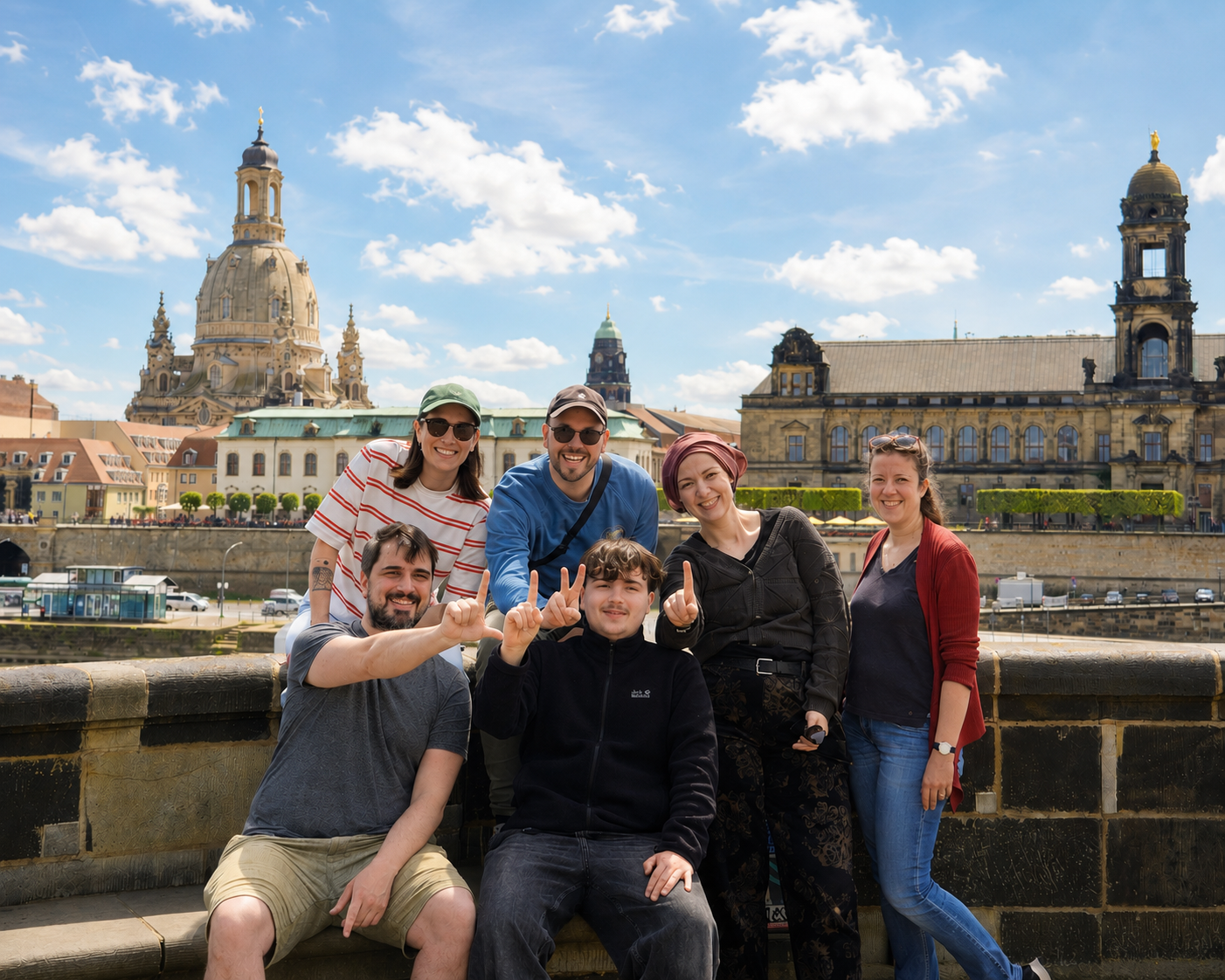 KI generiert: Das Bild zeigt eine Gruppe von fünf Personen, die auf einer Brücke stehen und in die Kamera lächeln, mit dem Hintergrund des historischen Prager Stadtbildes, einschließlich der Karlsbrücke und der Burg von Prag.