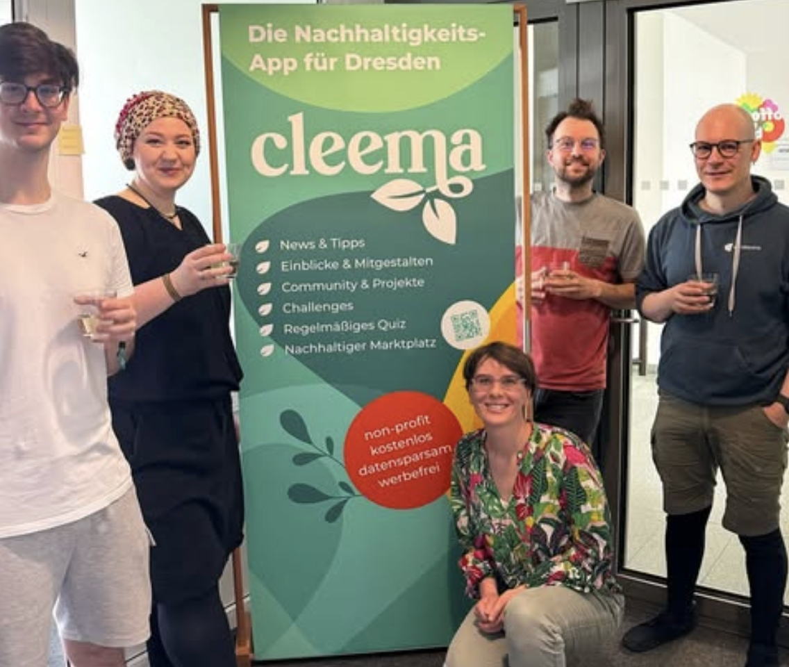 KI generiert: Eine Gruppe von fünf Personen steht um ein Plakat, das eine Nachhaltigkeits-App für Dresden namens "cleema" beschreibt. Das Plakat hebt verschiedene Funktionen der App hervor, wie News, Tipps, Community-Projekte und einen nachhaltigen Marktplatz.